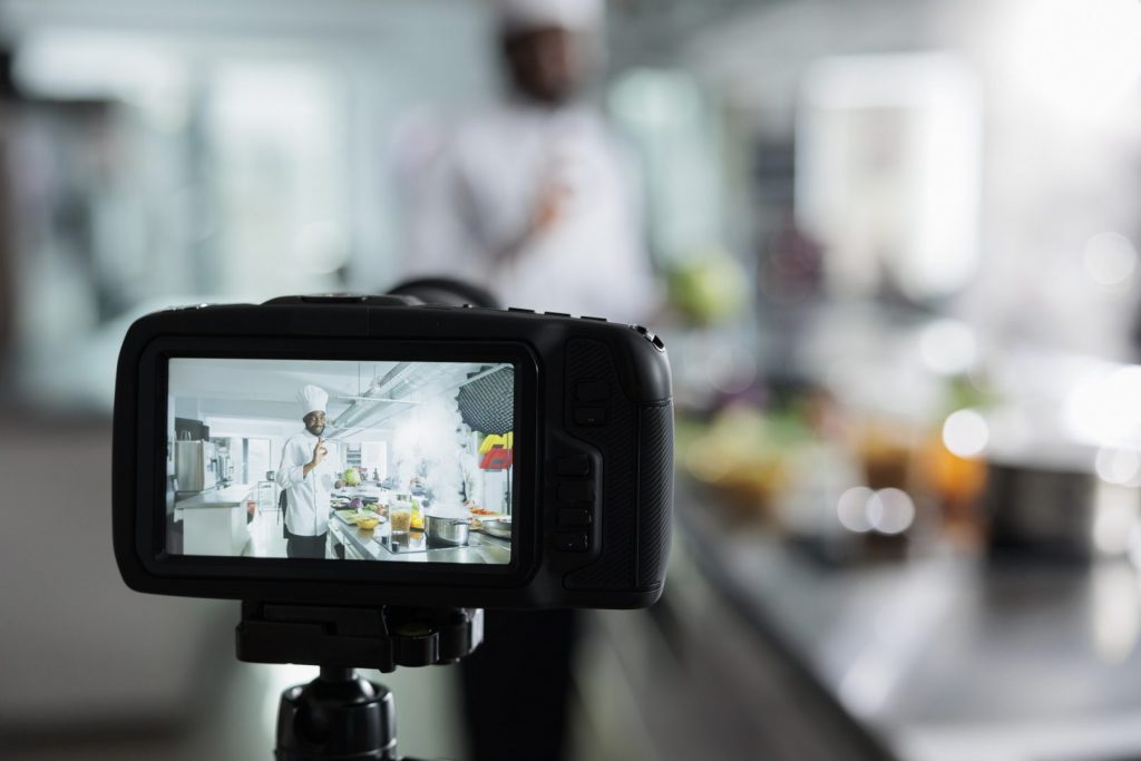 Close up camera recording gastronomy expert in restaurant kitchen filming culinary course
